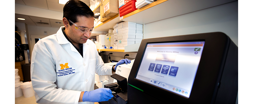 Muneesh Tewari, M.D., Ph.D. standing in front of a machine