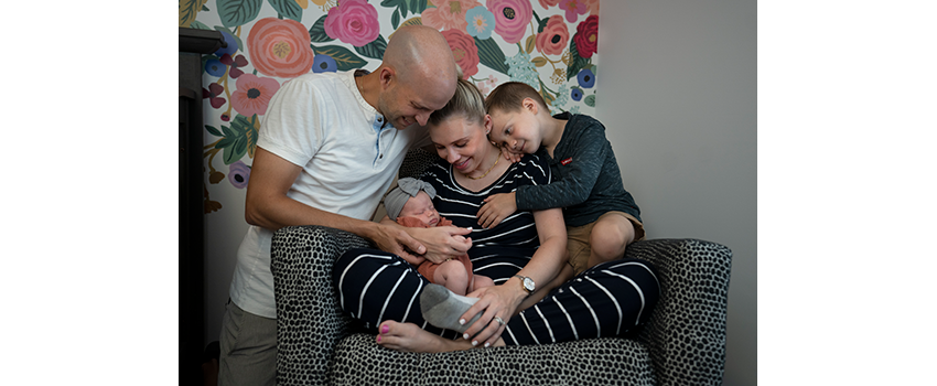 Leah, her husband and son sit together with the new baby