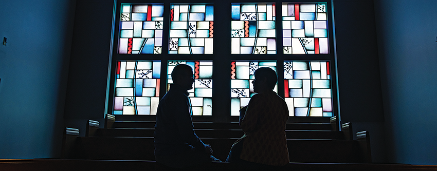 Tina Reuben in silhouette in front of a church's stained glass window