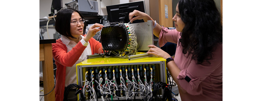 Zhen Xu,Professor of Biomedical Engineering at the University of Michigan (left) and Tejaswi Worlikar, Biomedical Engineering PhD student discuss the 700kHz, 260-element histotripsy ultrasound array transducer they use in Prof. Xu’s lab.