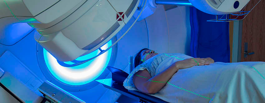 Black woman in a hospital gown lies on a scanning table